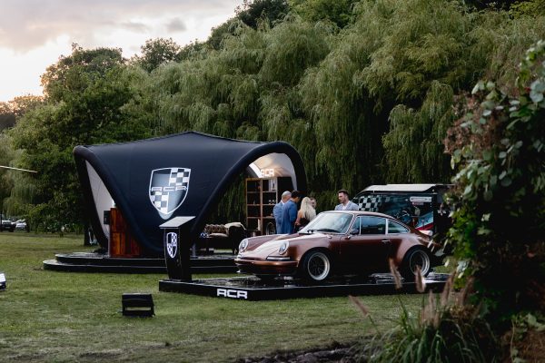 RCR restomod Porsche 911 showcased outdoors among greenery at a curated lifestyle event.