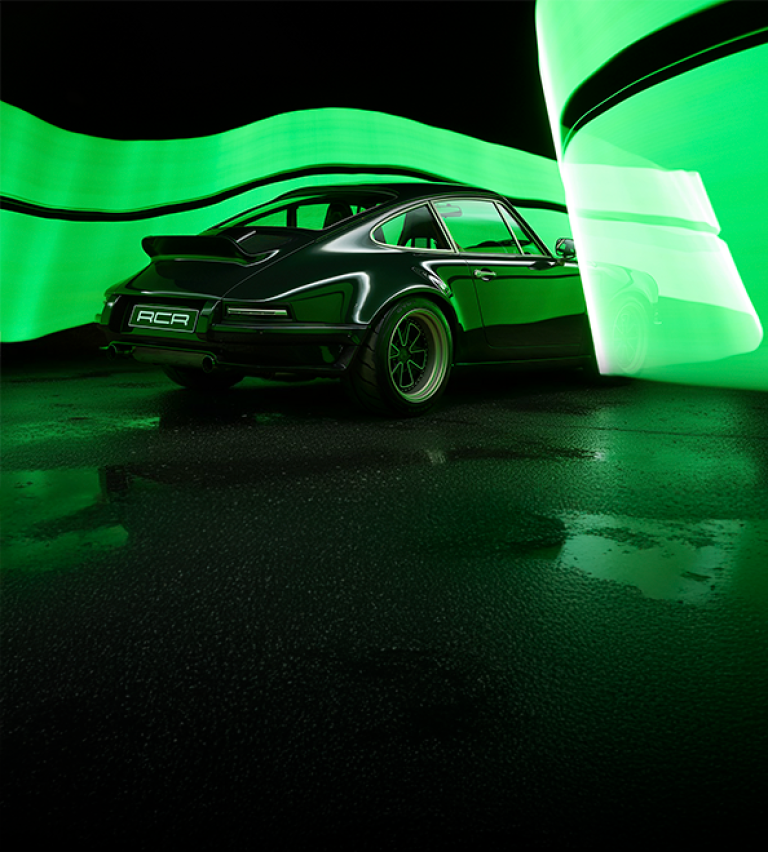 A sleek black sports car is parked on a wet surface, illuminated by vibrant green swirling lights in a dark, dramatic setting.